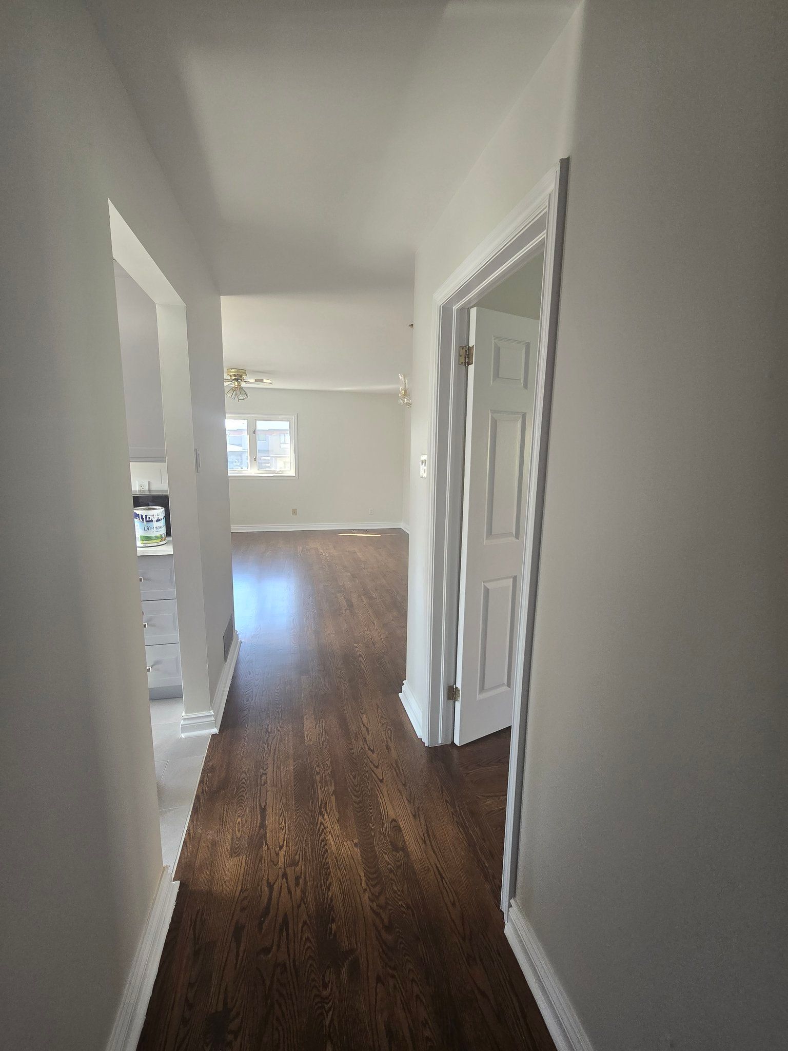 A hallway in a house with hardwood floors and white walls.