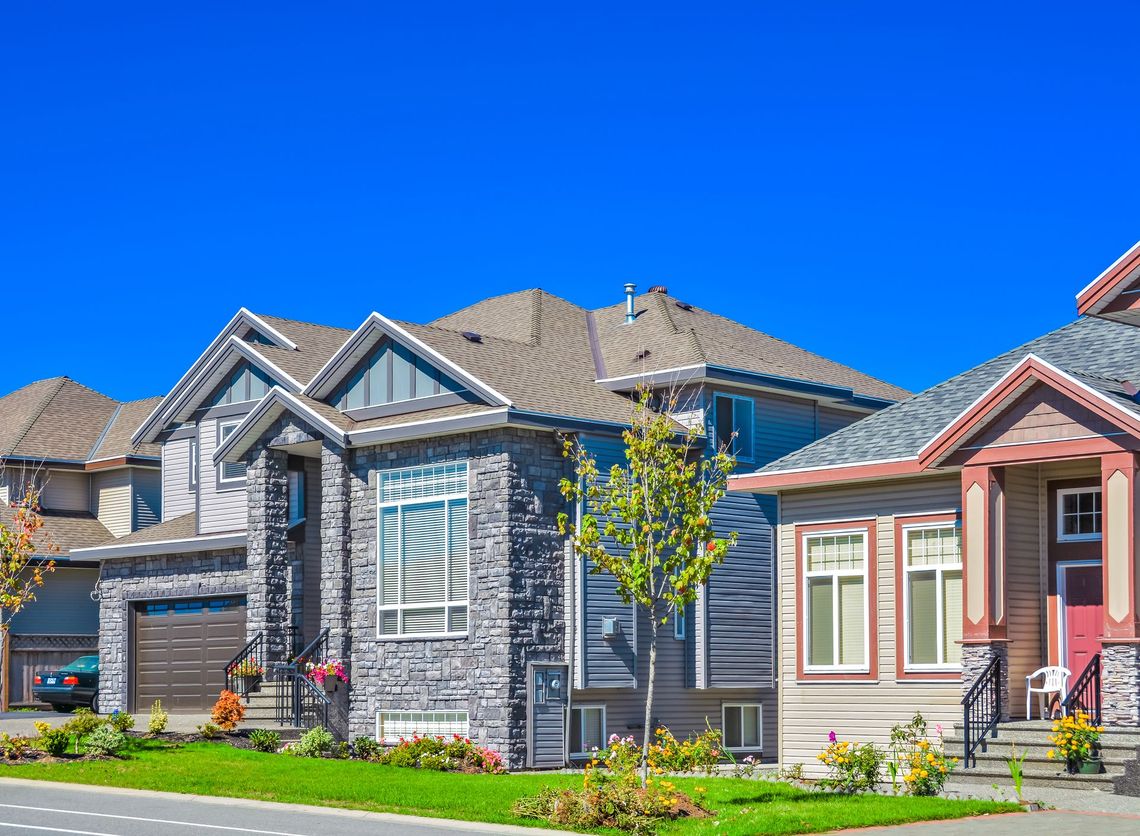 A row of houses on a sunny day with a blue sky in the background.