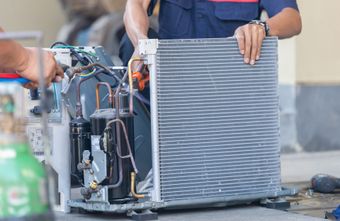 Un homme travaille sur un climatiseur à l'extérieur d'un bâtiment.