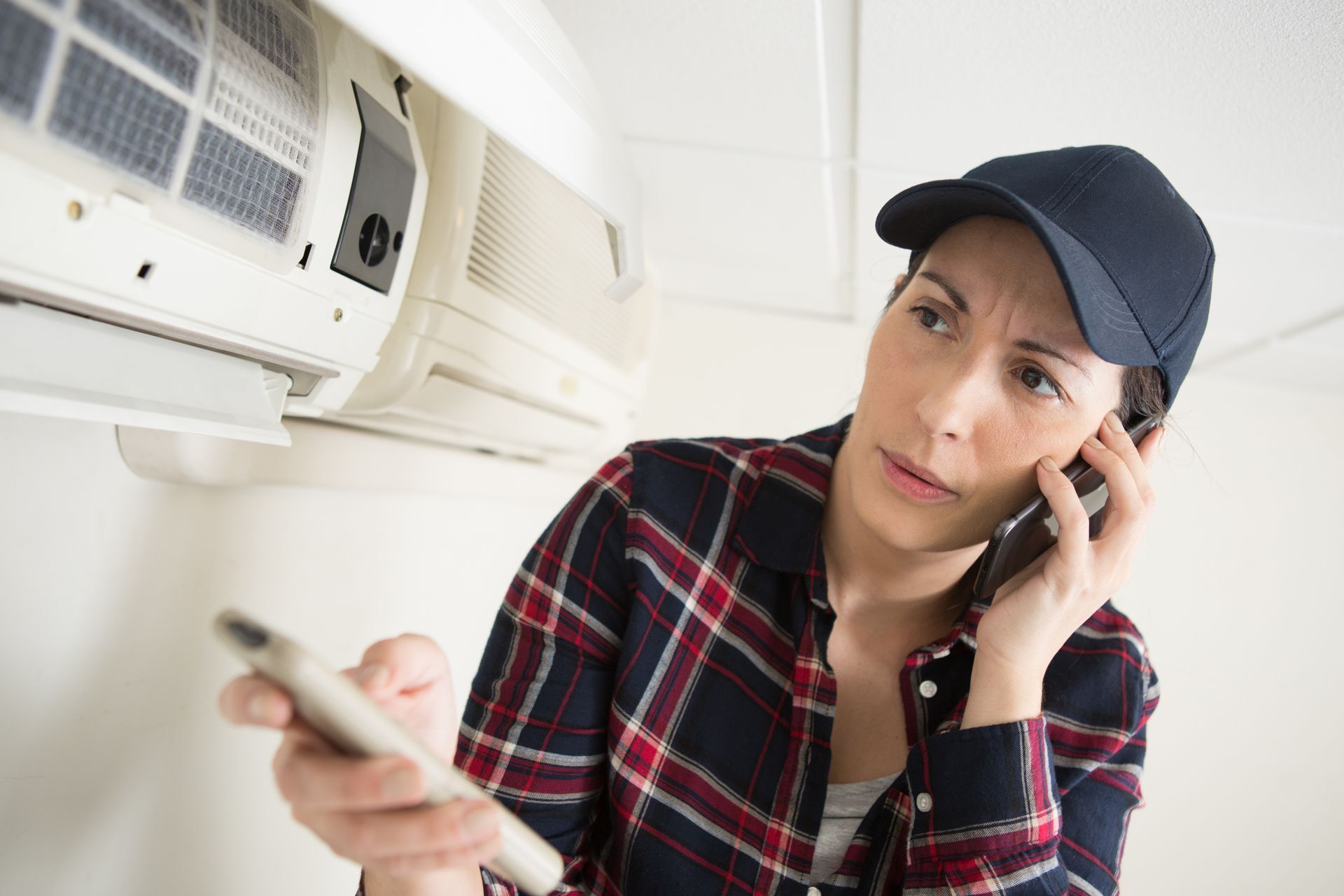 Une femme parle au téléphone portable tout en regardant un climatiseur.