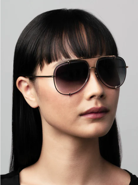 Woman wearing dark aviator sunglasses, with a slight smile.