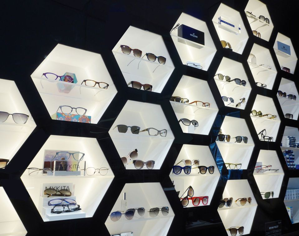 Display of eyeglasses in illuminated hexagon-shaped shelves.