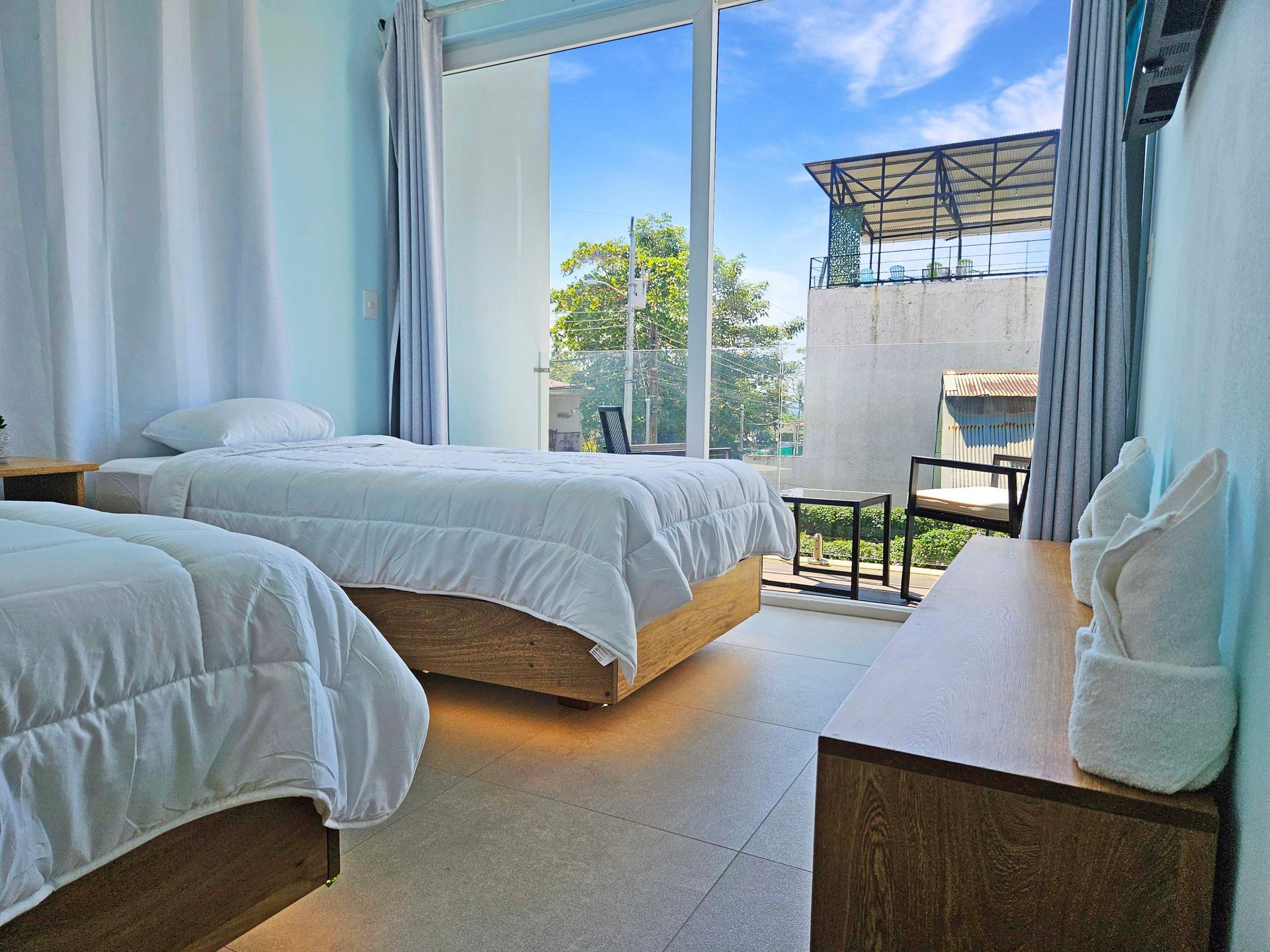 Bedroom with two twin beds, large window with a view, and wooden furniture.