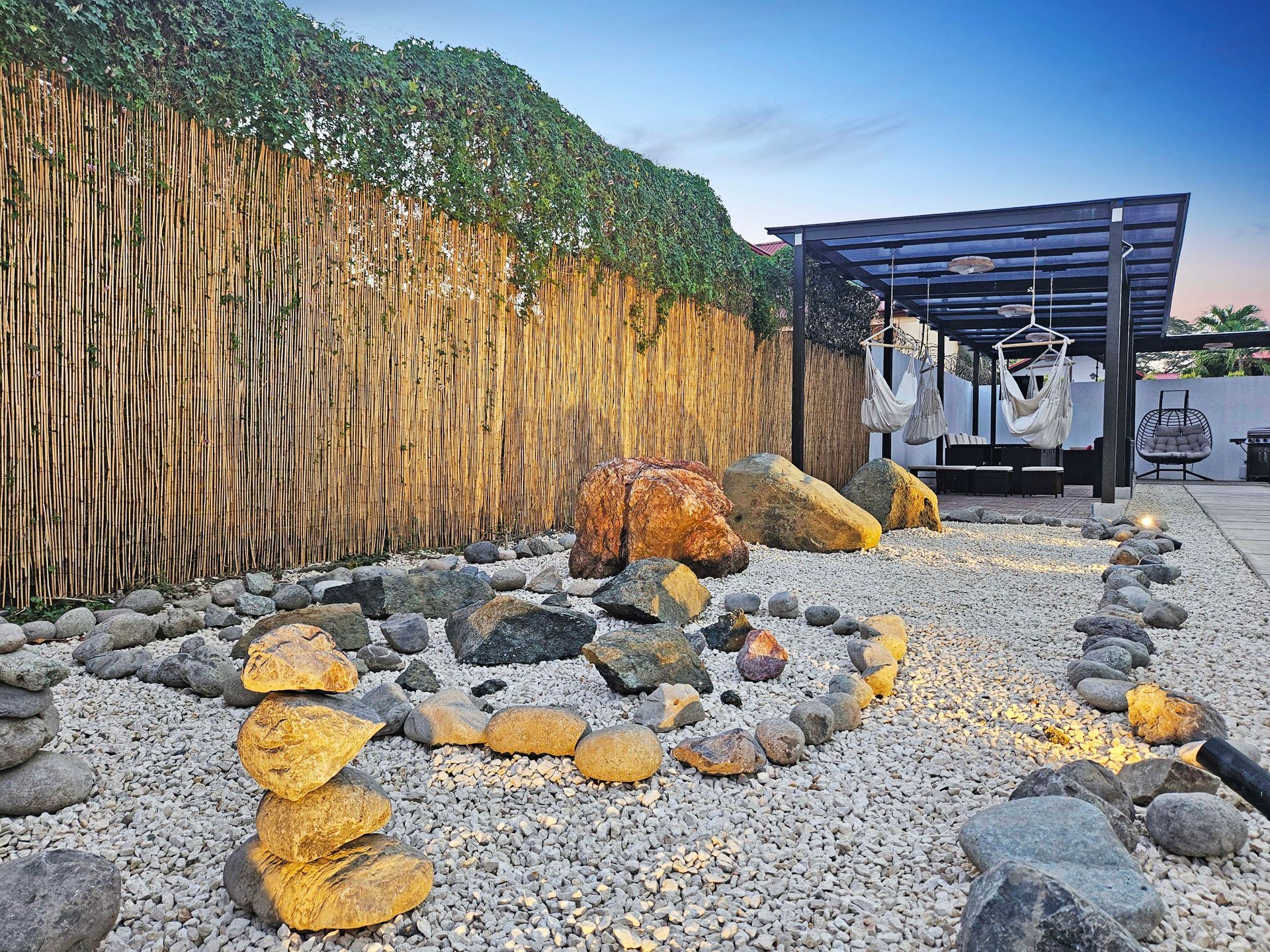 Zen garden with stone pathway, rocks, wooden fence, and pergola.