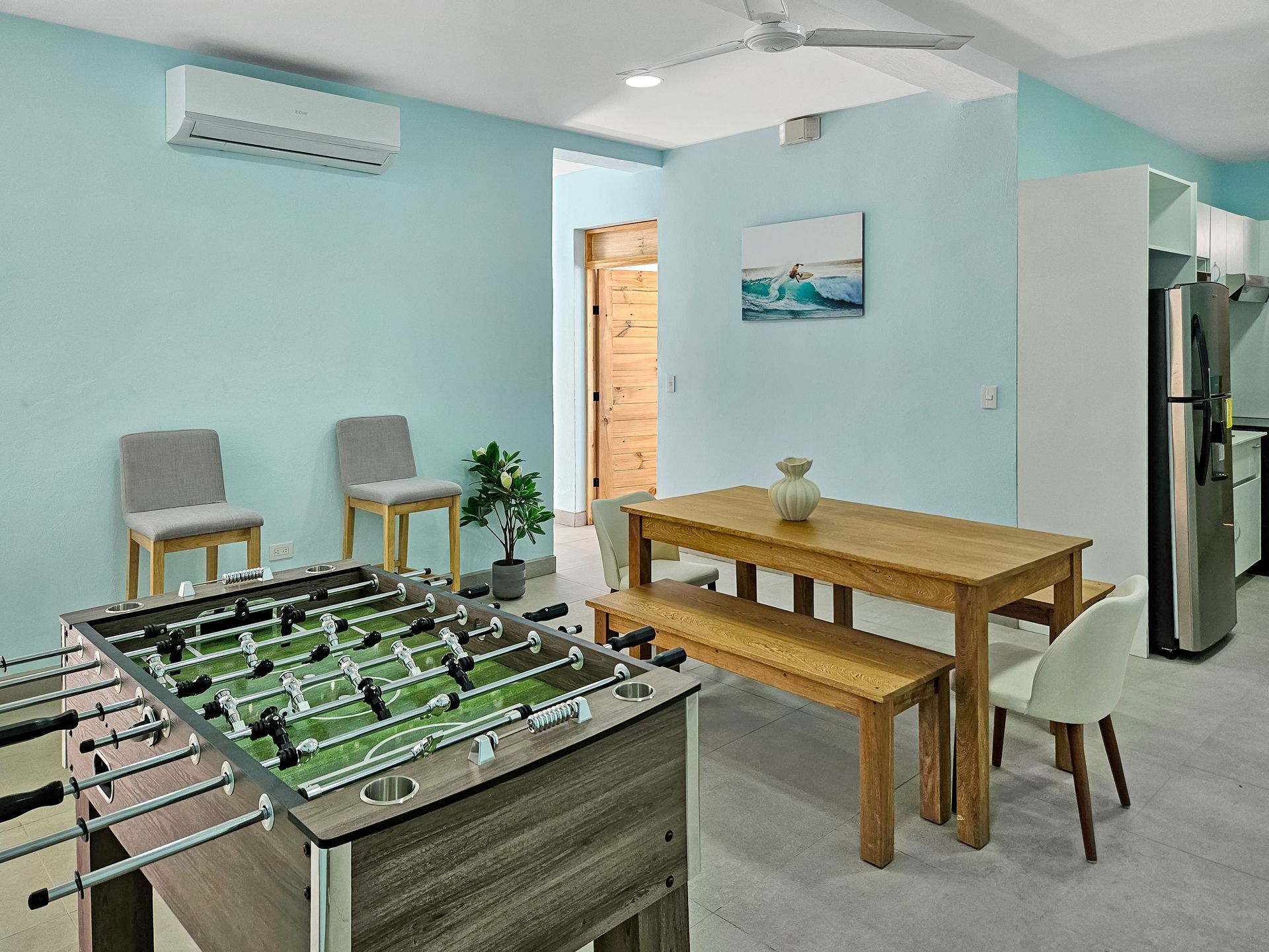 Foosball table and dining area with blue walls, two chairs, a bench, and a table.