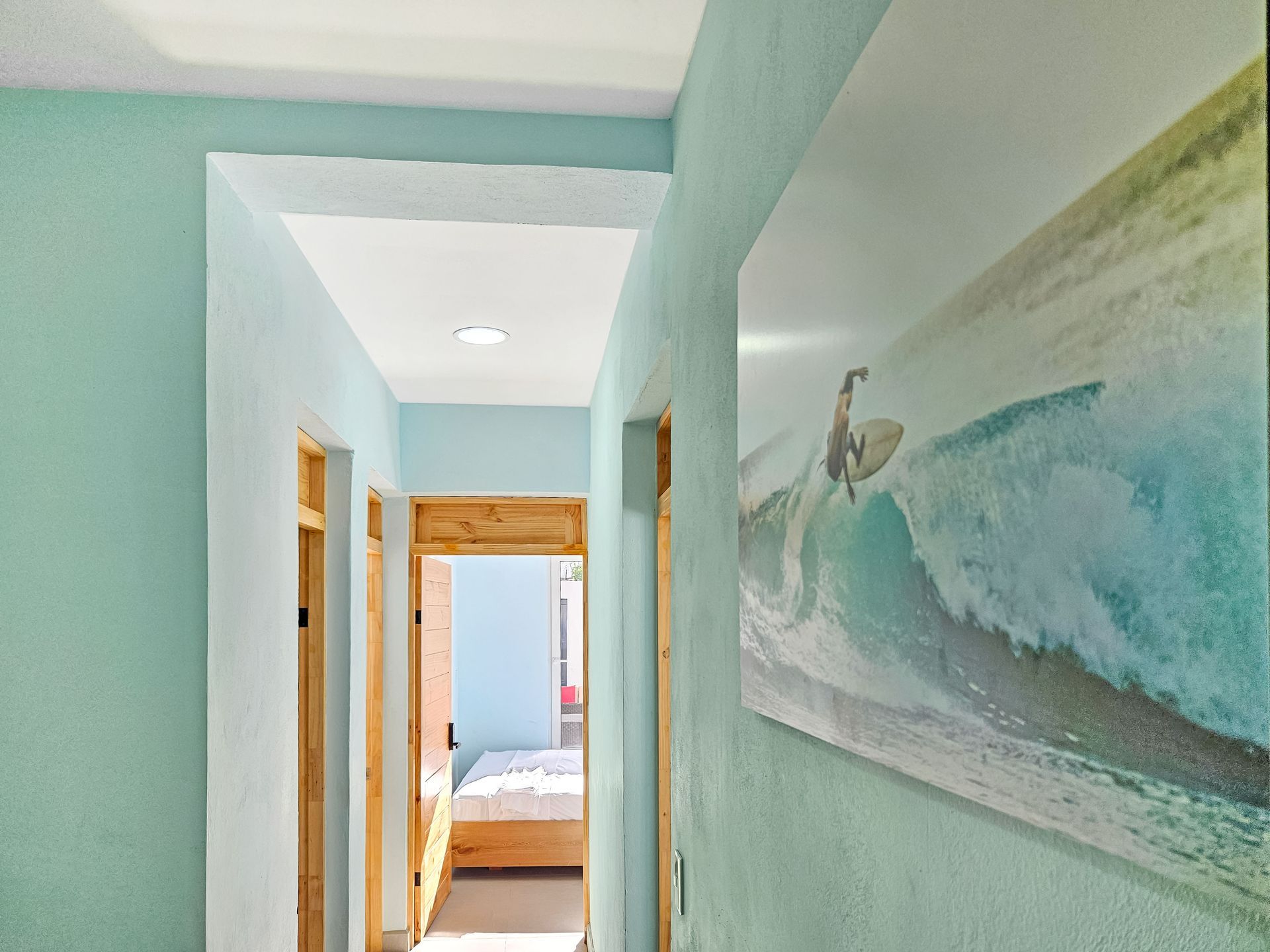 Hallway with light blue walls, wooden doorways, and a surfing photo.