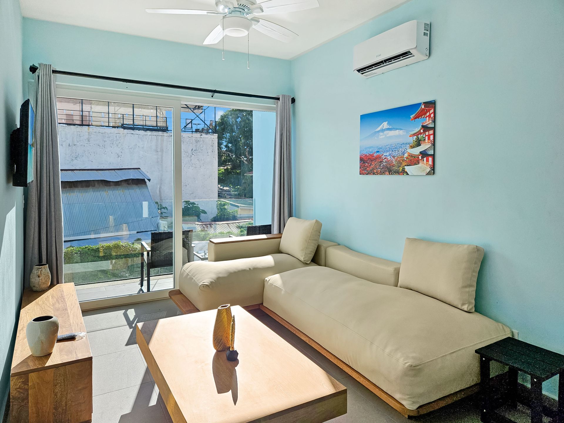 Living room with light blue walls, beige sectional sofa, and glass door to a patio.