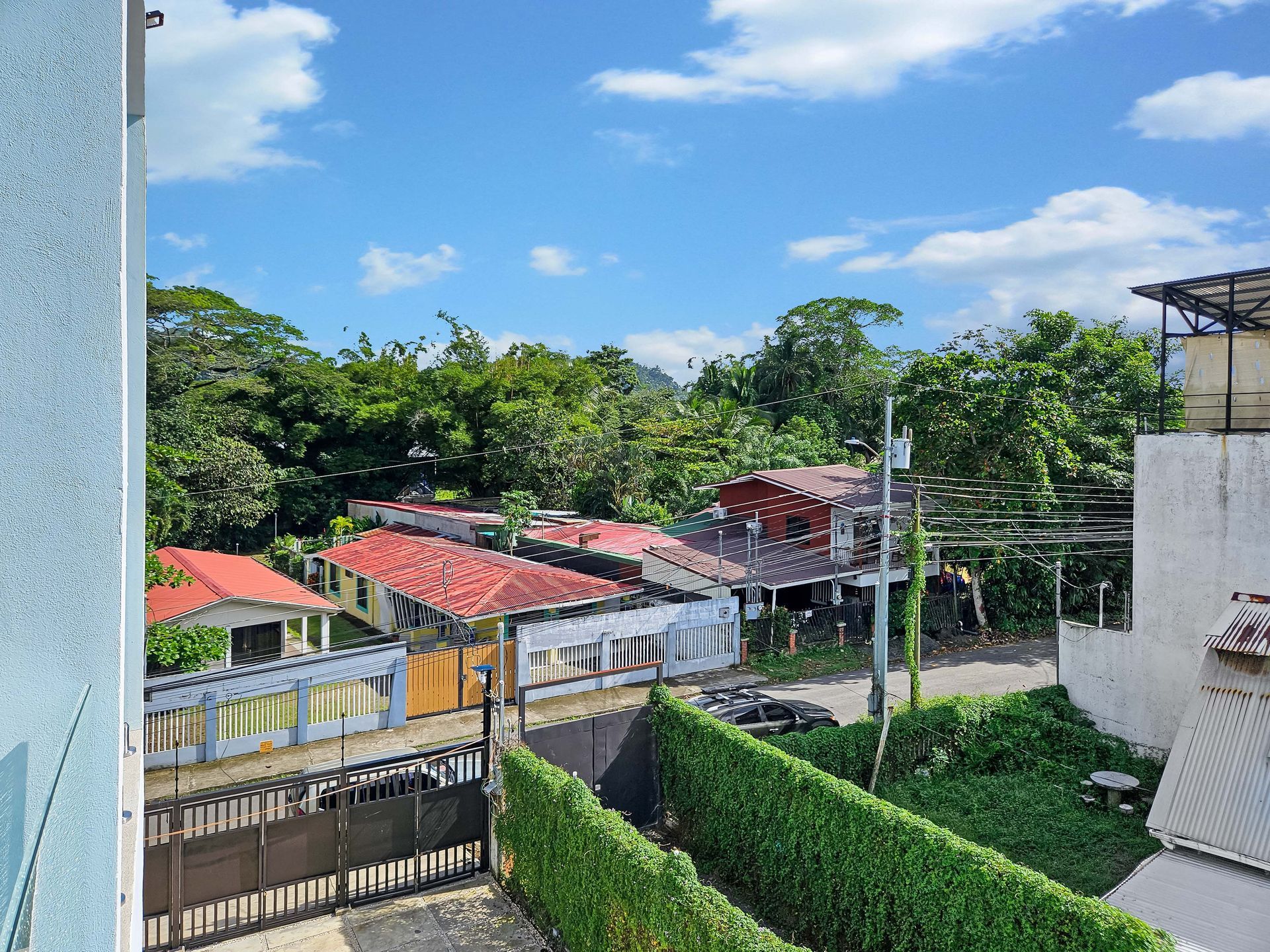 View of colorful houses, lush trees, and blue sky from a building's window.