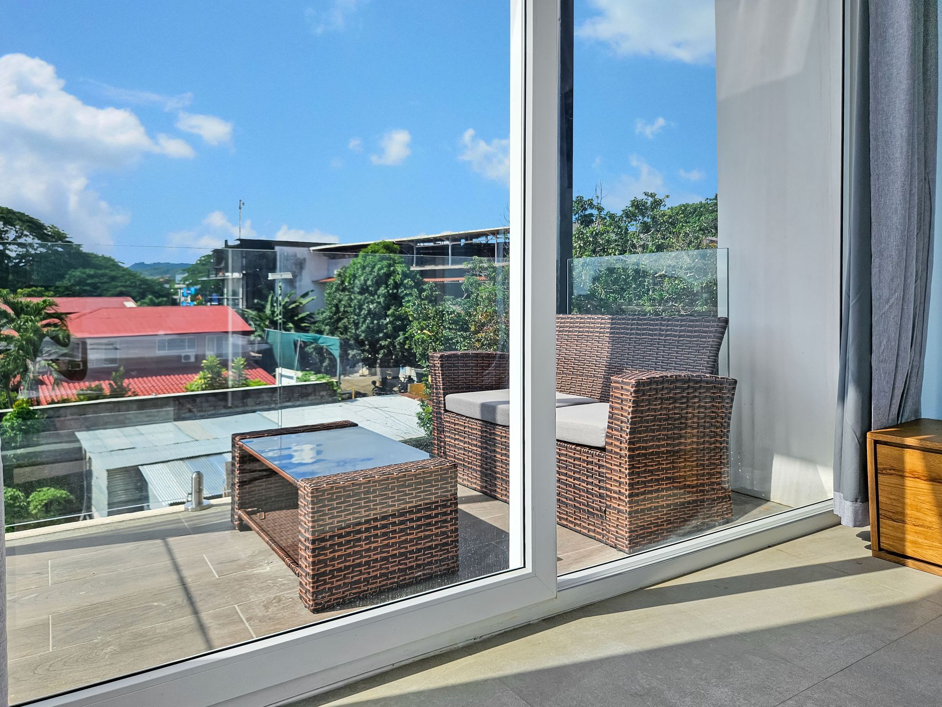 Patio with wicker furniture, overlooking a cityscape with blue sky.