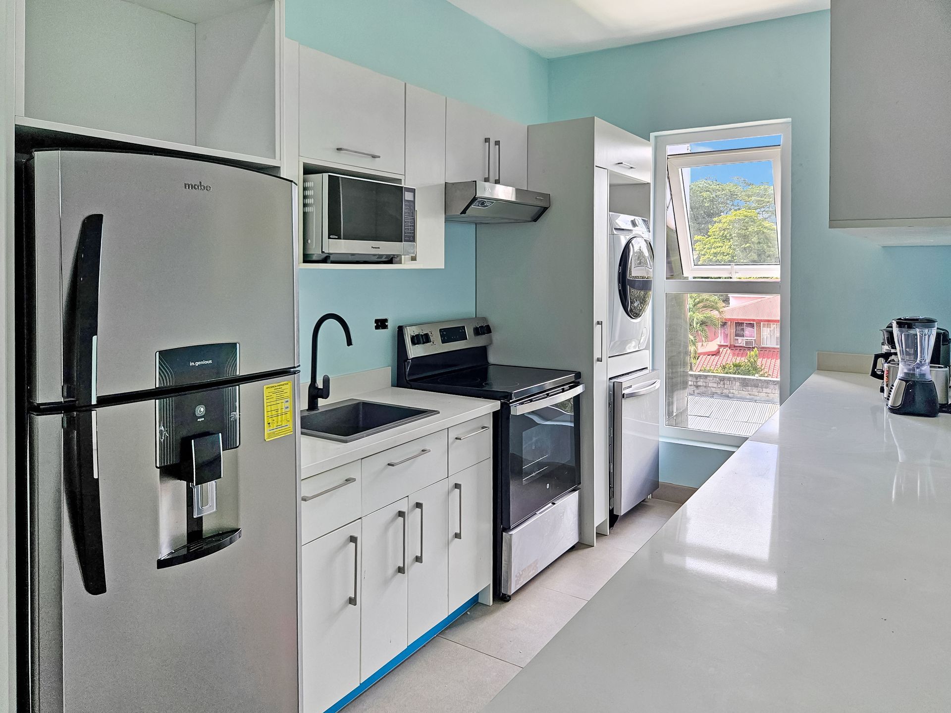 Modern kitchen with stainless steel appliances, white cabinets, and a window.