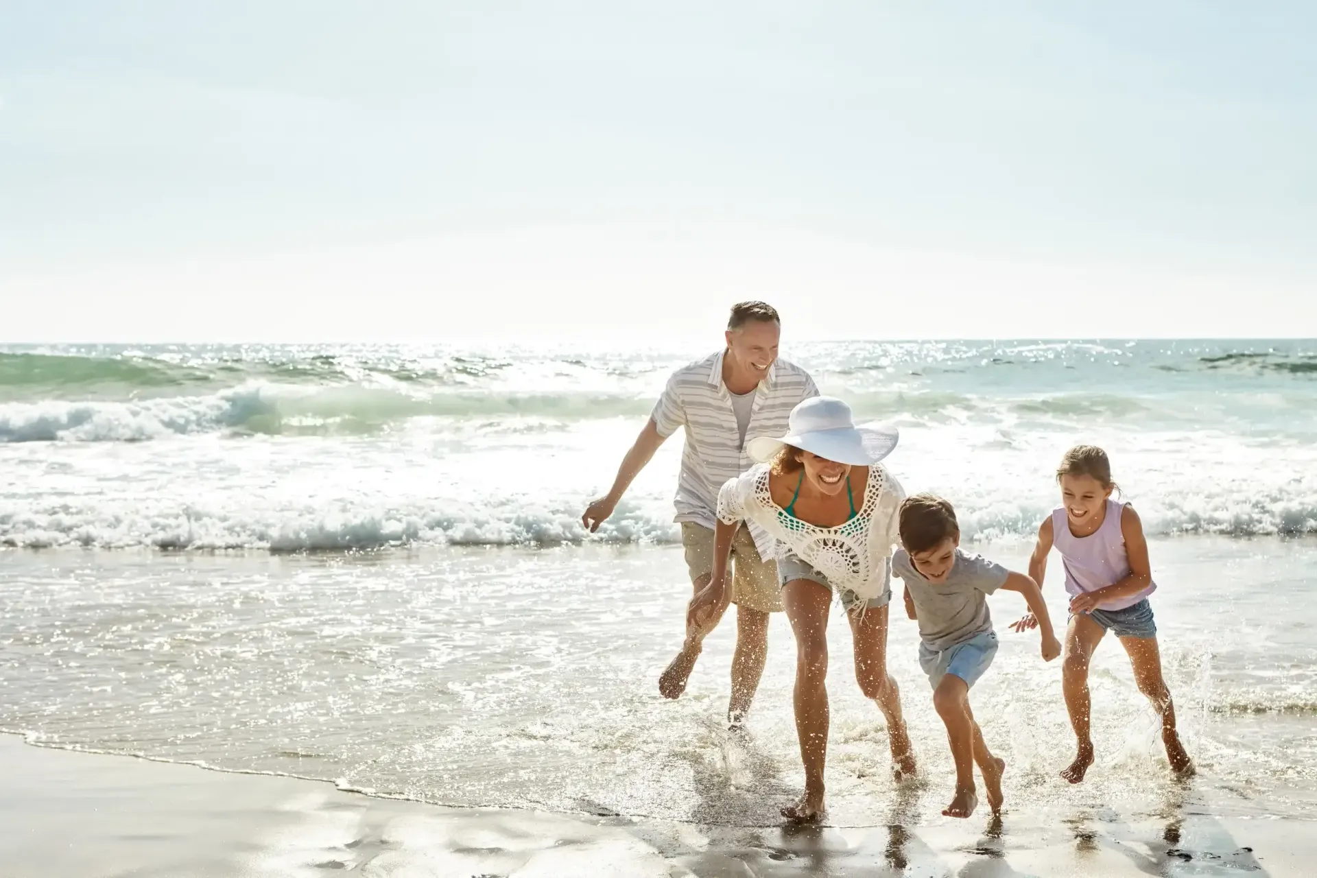 Family splashing in ocean waves on a sunny beach.