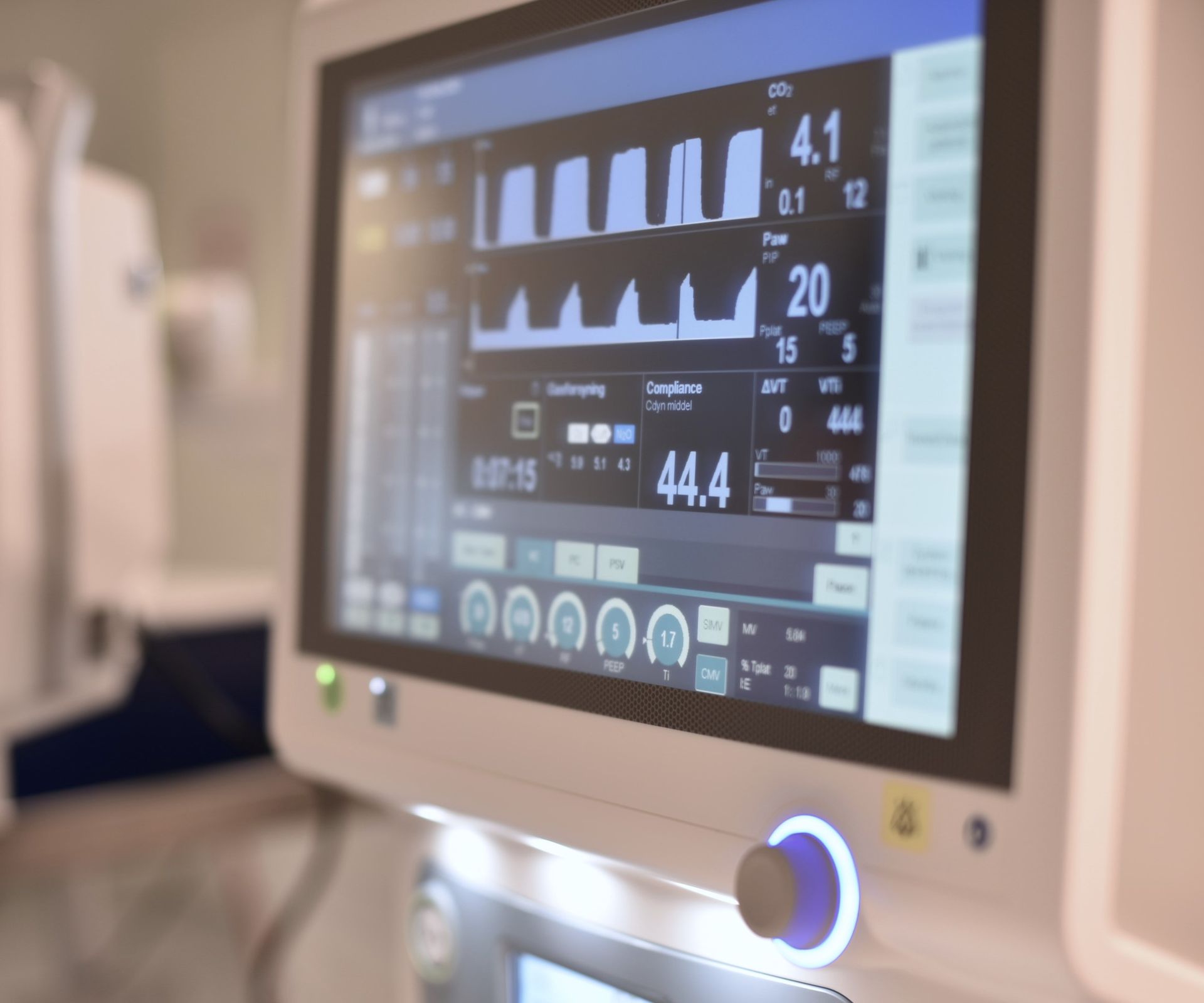 Medicinsk monitor som visar vitala tecken och vågformer i en sjukhusmiljö.