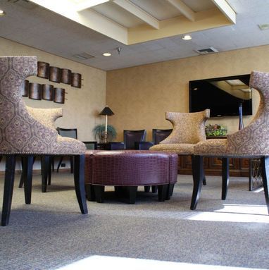 A living room with chairs ottomans and a flat screen tv
