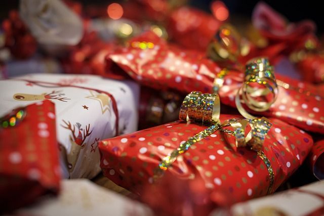 Pile of wrapped Christmas presents in red, white, and gold, with ribbons and bows.