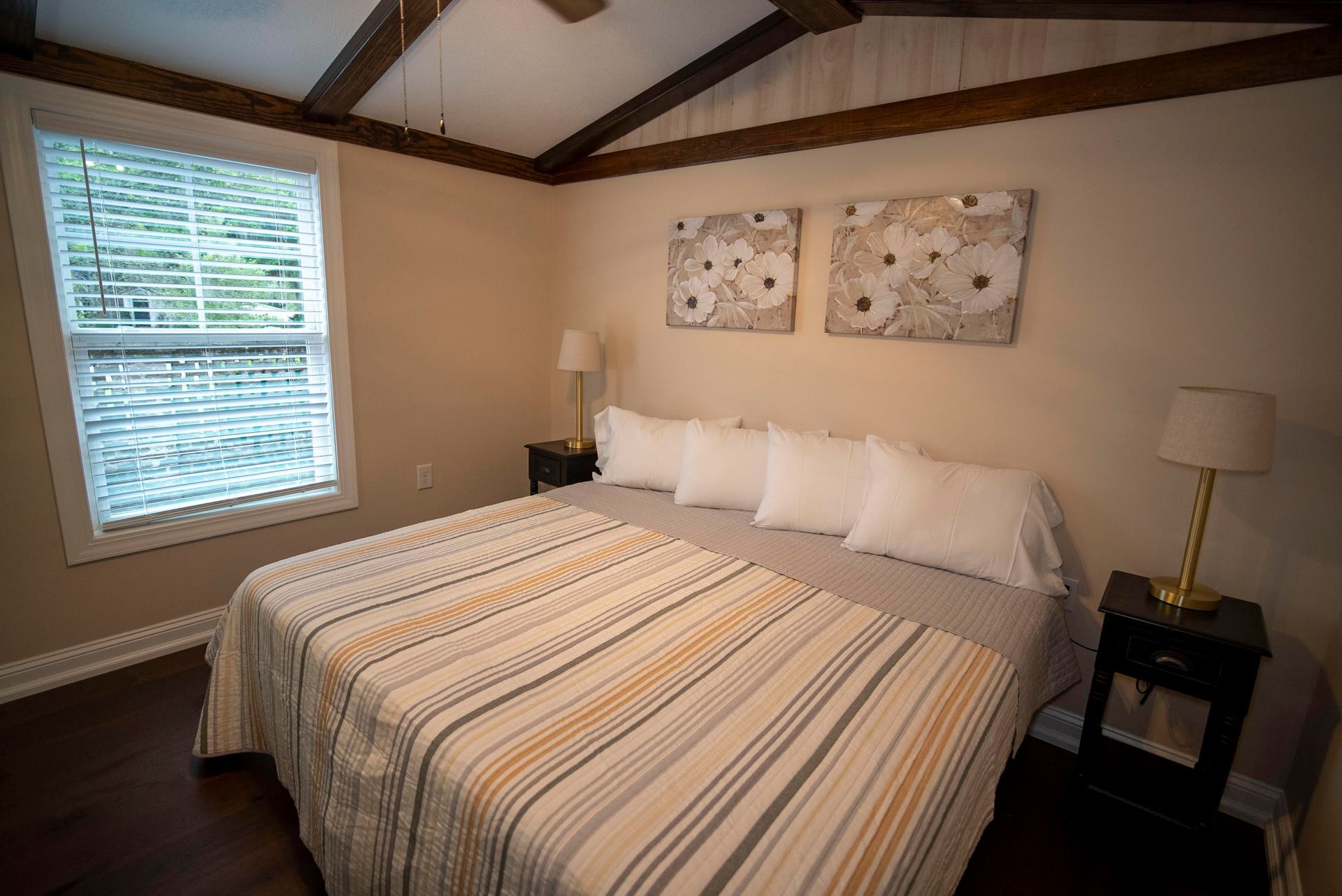A bedroom with a bed , two nightstands , two windows and a ceiling fan.