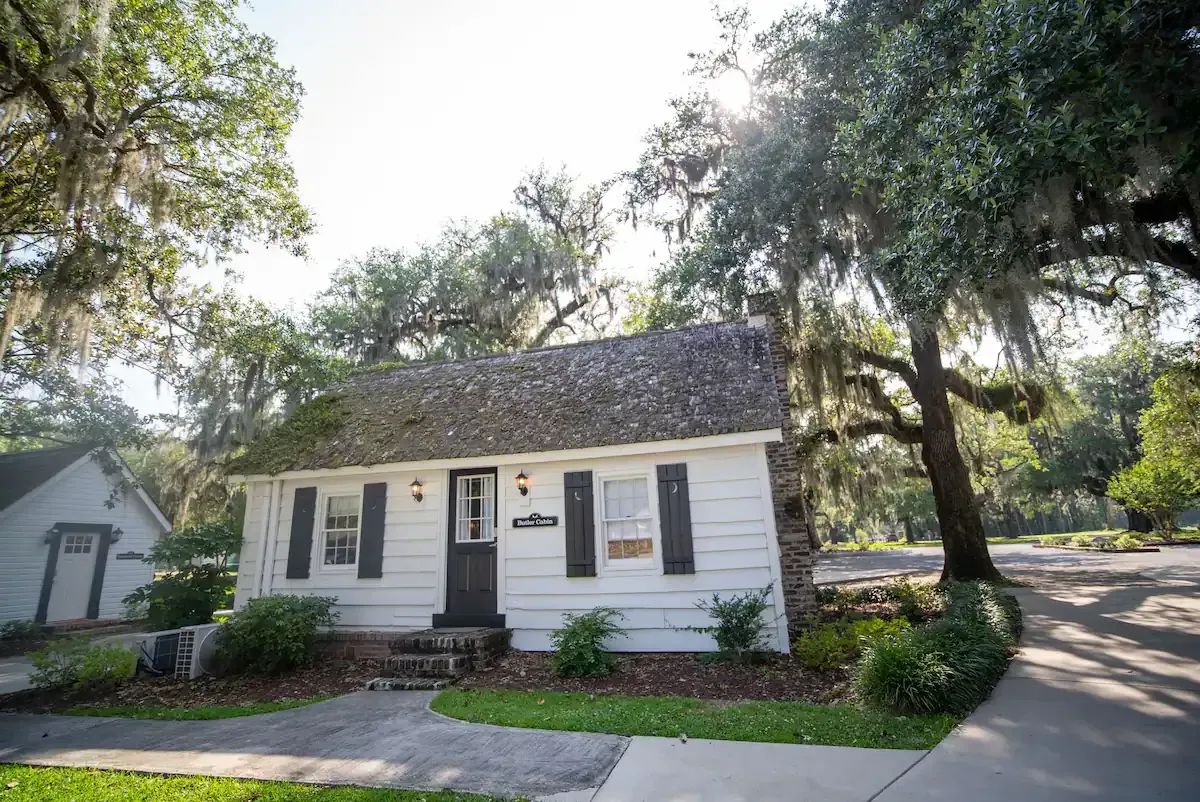 a small white house with black shutters is surrounded by trees