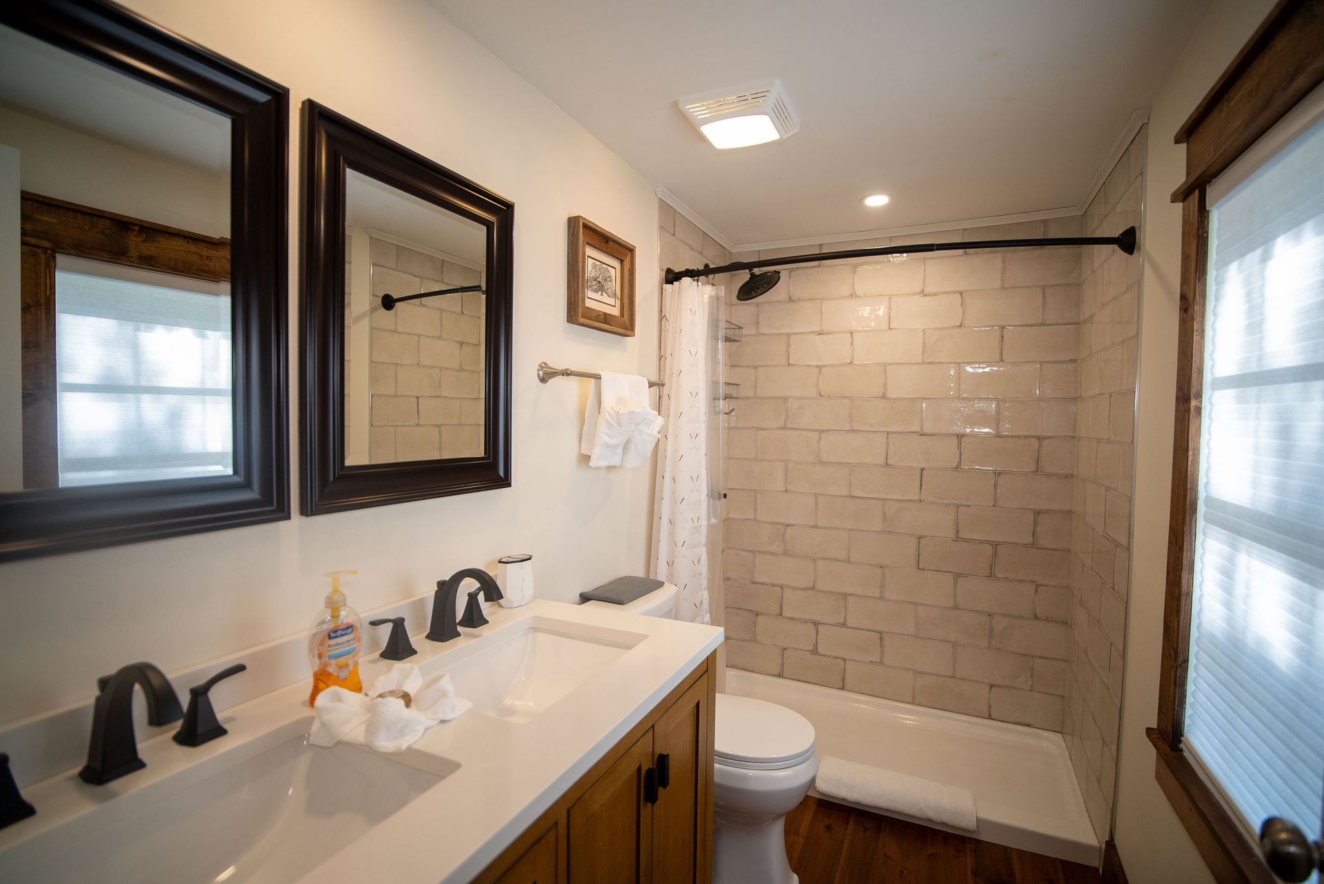 a bathroom with a sink , toilet , shower and two mirrors .