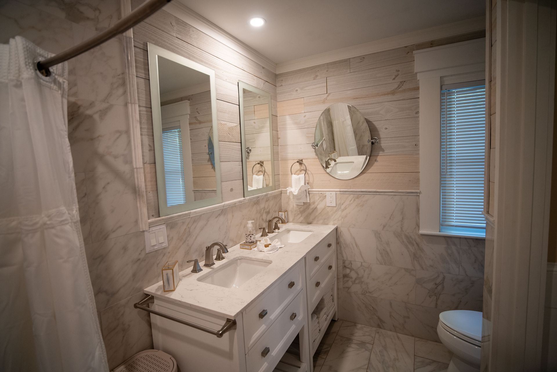 a bathroom with two sinks , a toilet and a mirror .