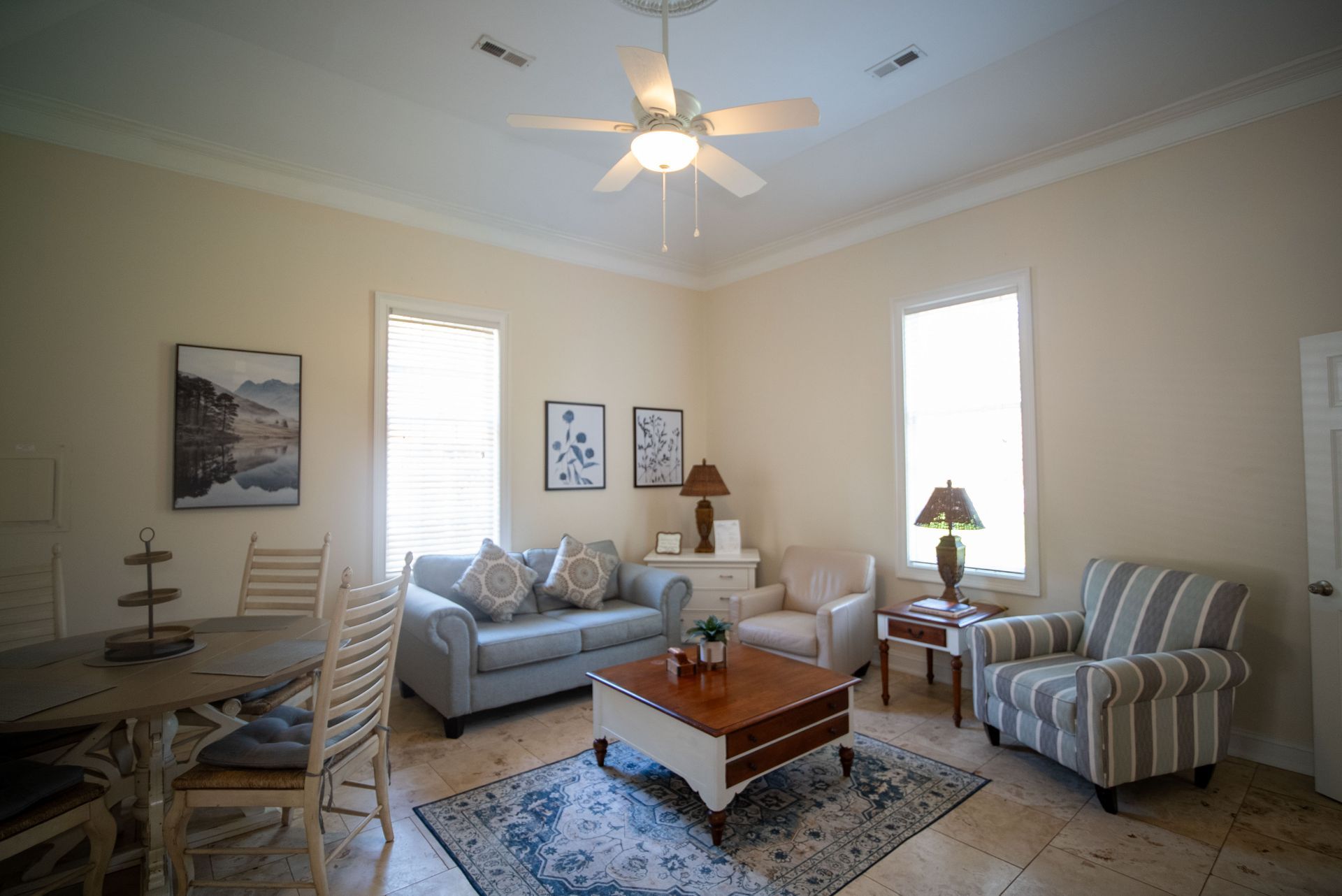 a living room with a couch , chairs , table and ceiling fan .