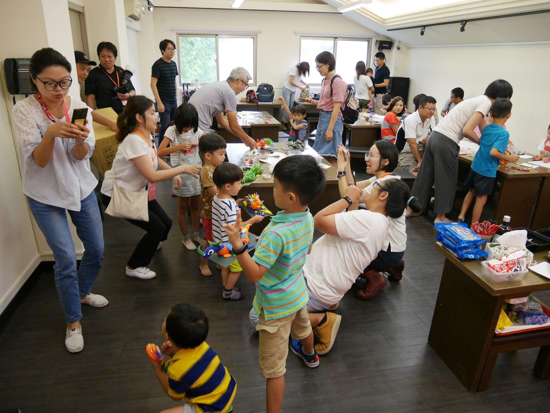 孩子和大人一起在擠滿玩具和氣球的室內房間裡玩耍。