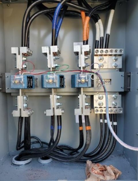 Electrical wiring in a metal box. Black, orange, blue, and white wires connect to gray terminals.