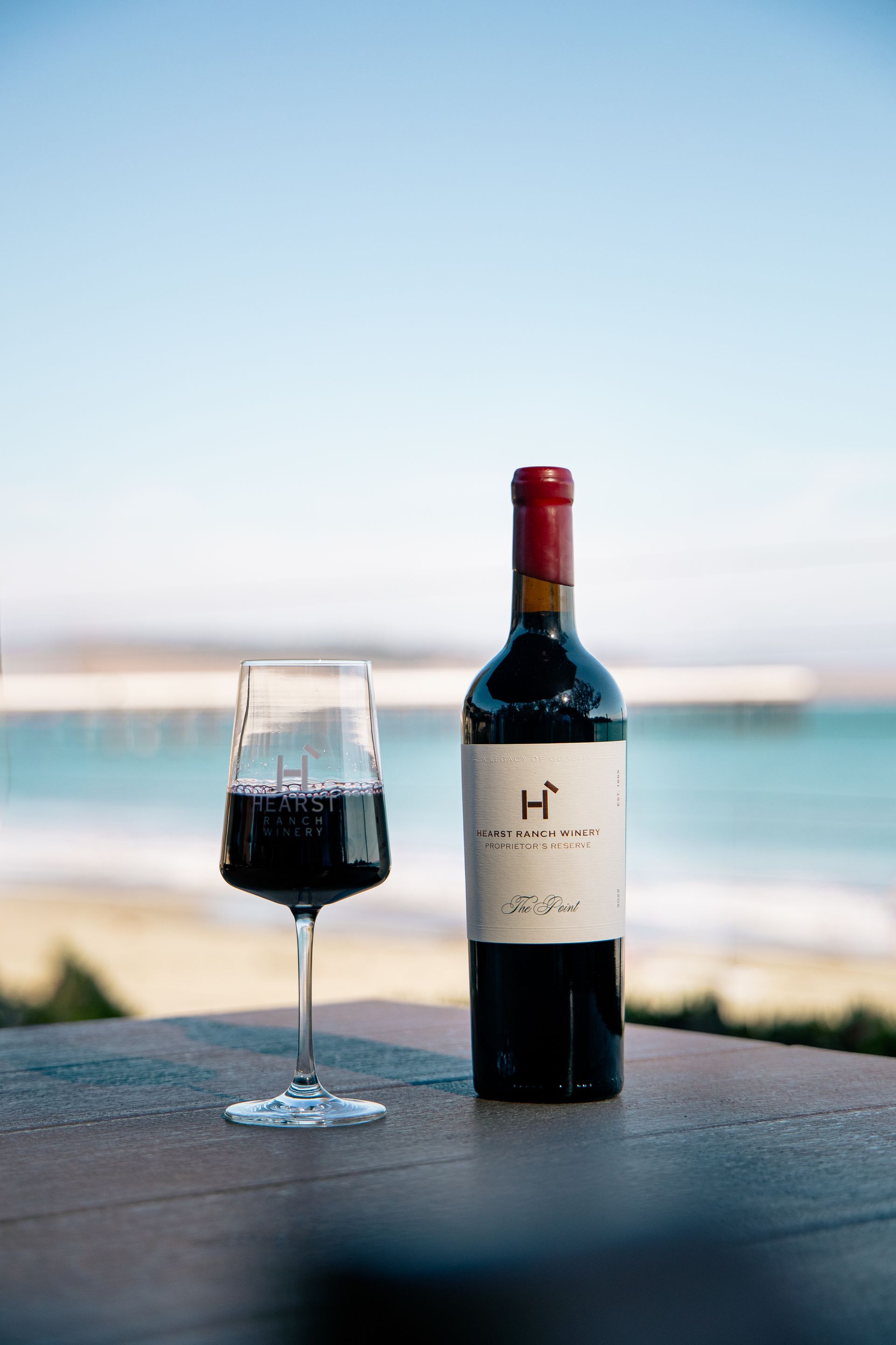 Two wine glasses being filled, one with white wine and one with red wine, against a warm background