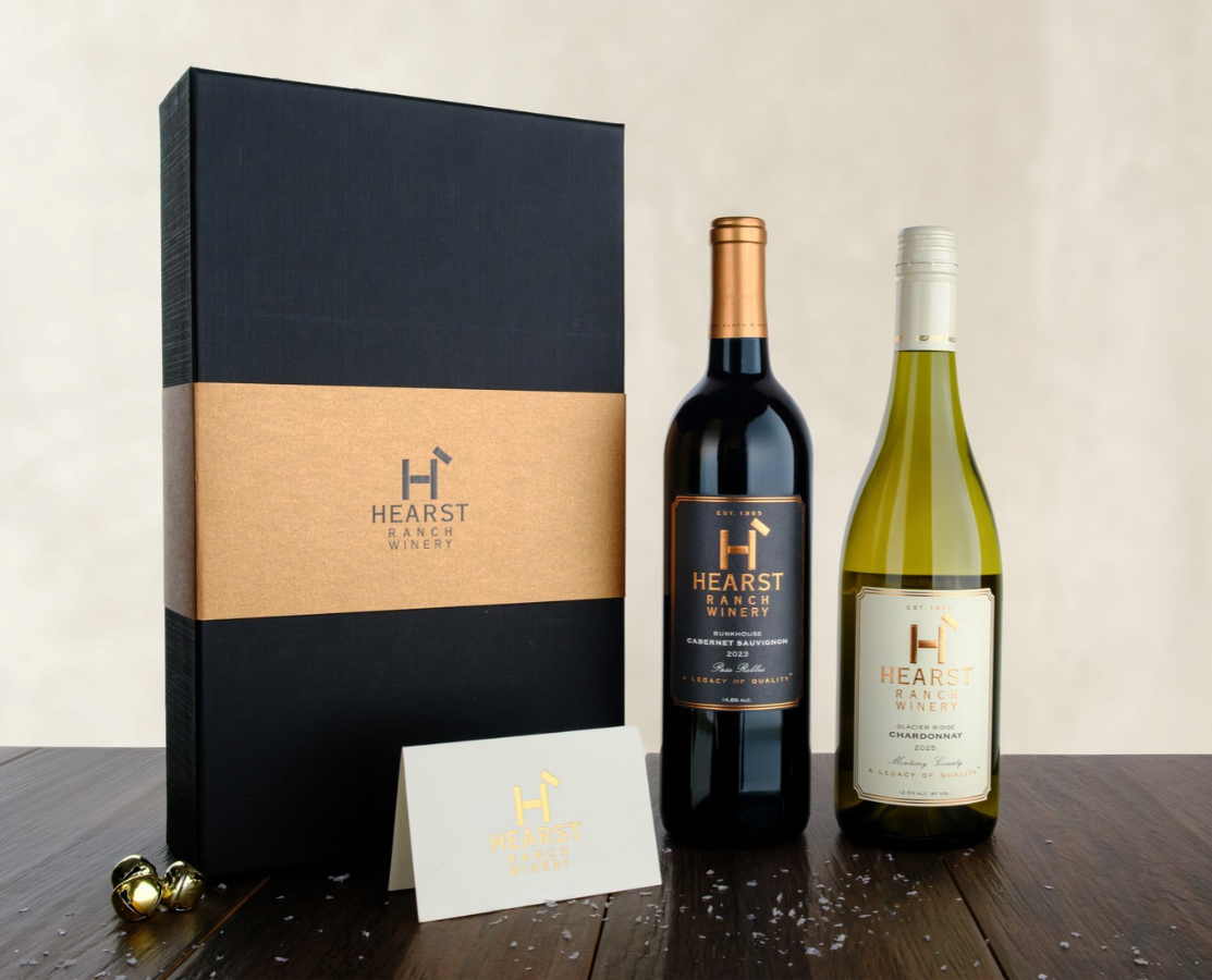 Bottle of white wine with a cream label and gold foil top on a plain background