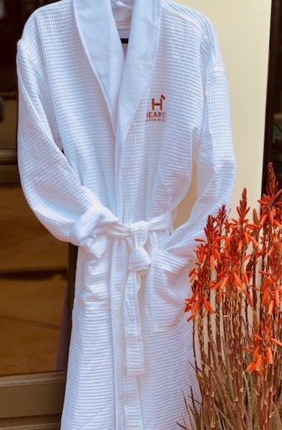 White bathrobe hanging indoors beside orange flowers