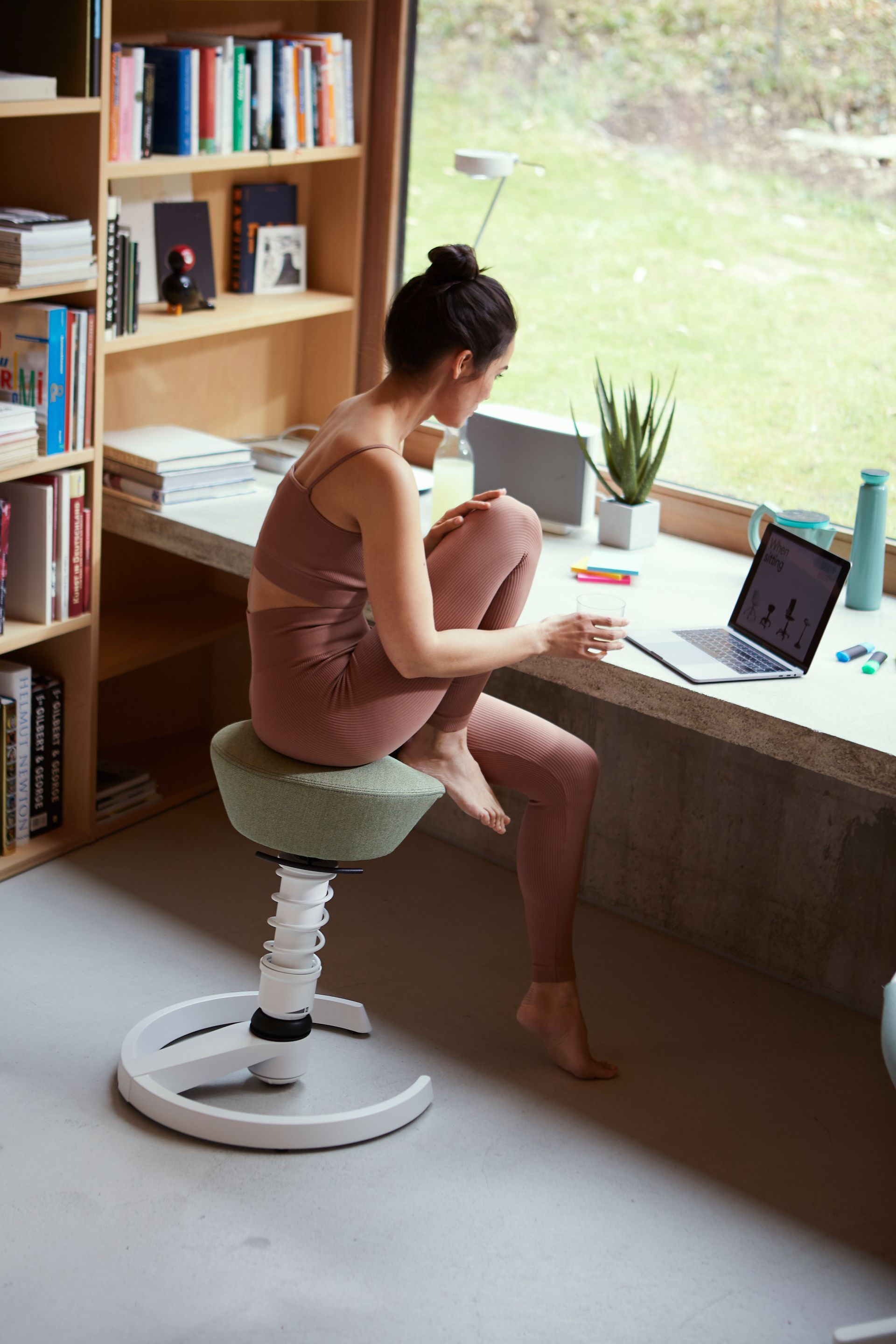 Frau arbeitet entspannt auf einem ergonomischen Swopper-Hocker am Laptop
