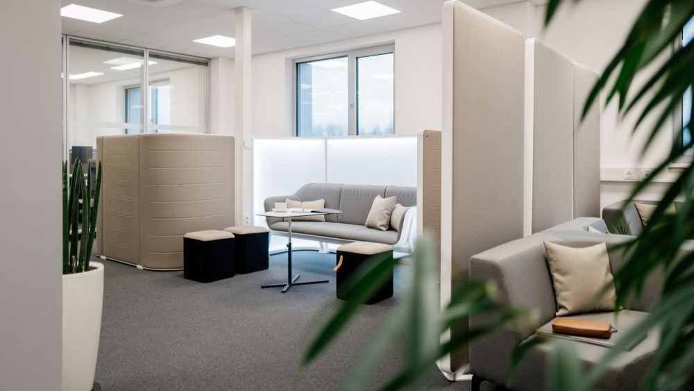 Helles Büro mit abgetrennten Arbeitsplätzen und Loungesessel
