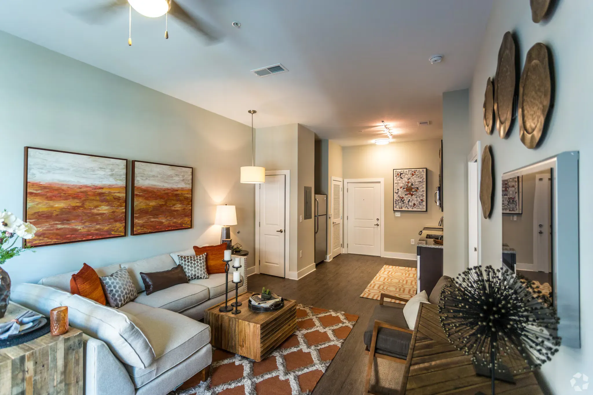 Living room in a modern apartment with a gray sectional, wooden coffee table, and wall art.