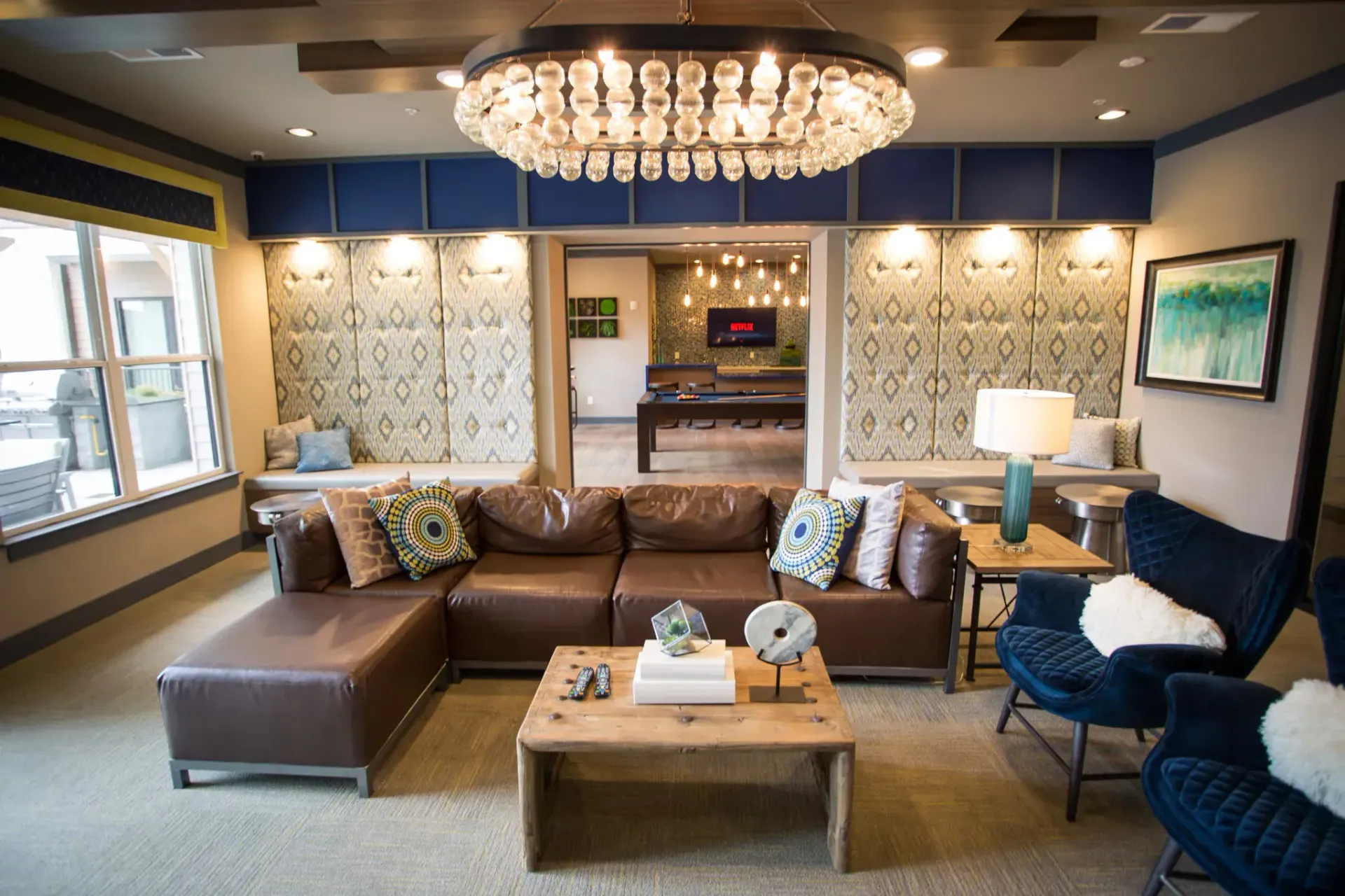 Spacious resident lounge with a brown sectional sofa, coffee table, and decorative lighting.