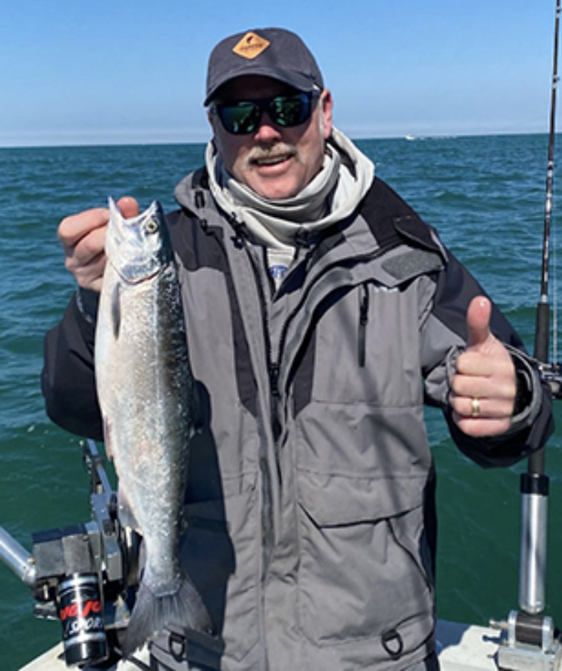 A man is holding a fish and giving a thumbs up
