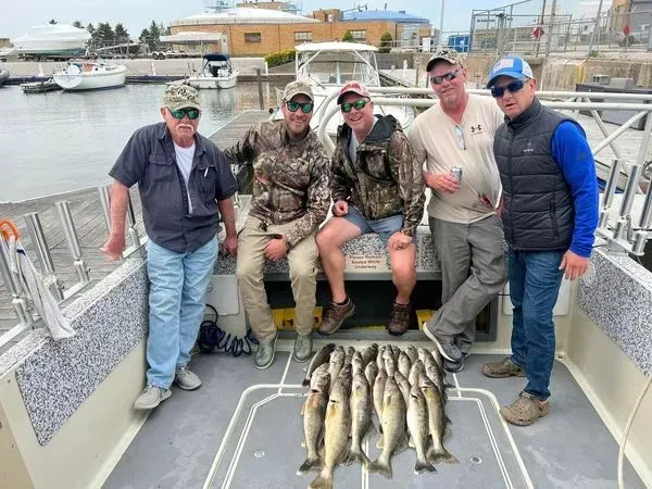A group of men are standing on a boat with a bunch of fish on the deck.