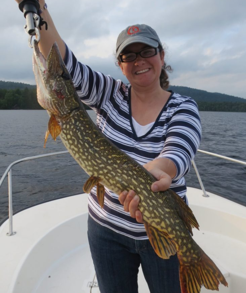 A woman on a boat is holding a large fish