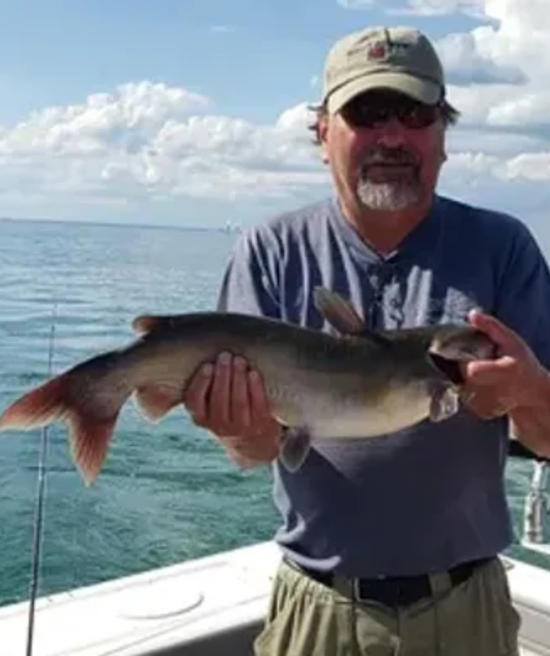 A man is holding a fish in his hands on a boat.