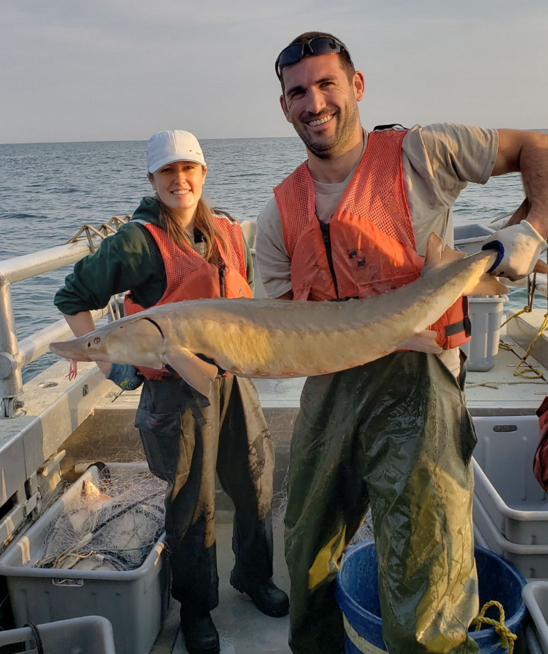 A man and a woman on a boat holding a large fish