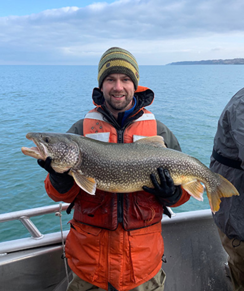 A man is holding a large fish on a boat.