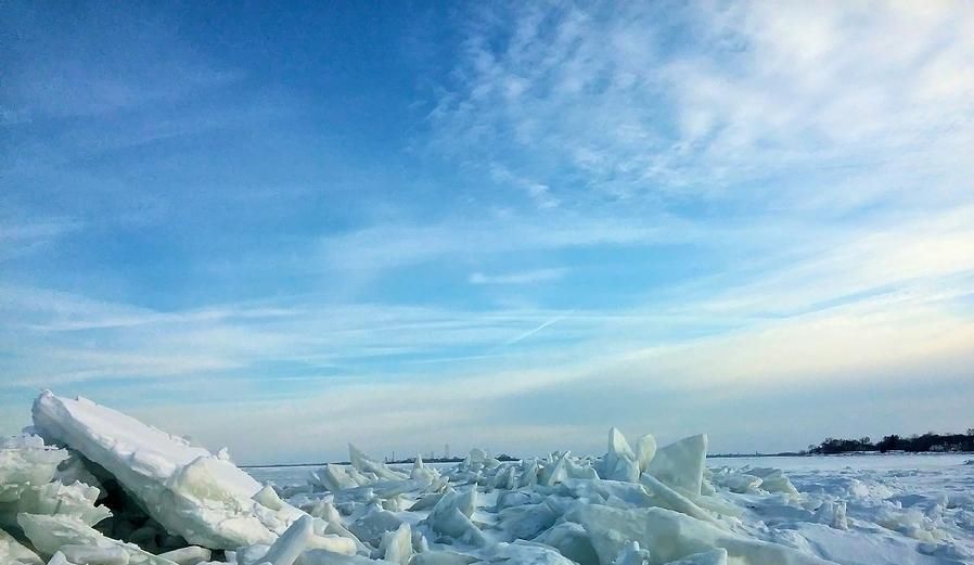 A pile of ice on a beach with a blue sky in the background.