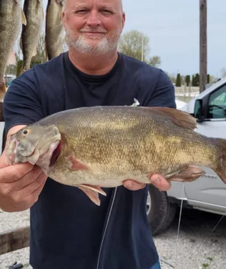 A man is holding a large fish in his hands