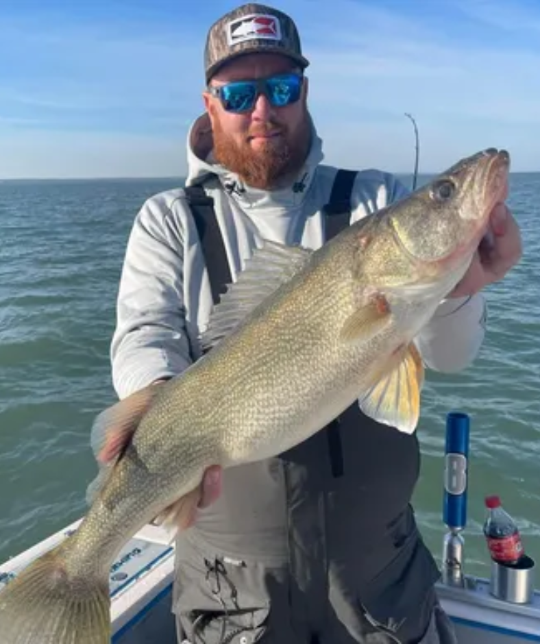 A man is holding a large fish on a boat.