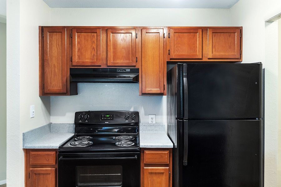 A kitchen with wooden cabinets, a black stove, and a matching black refrigerator.
