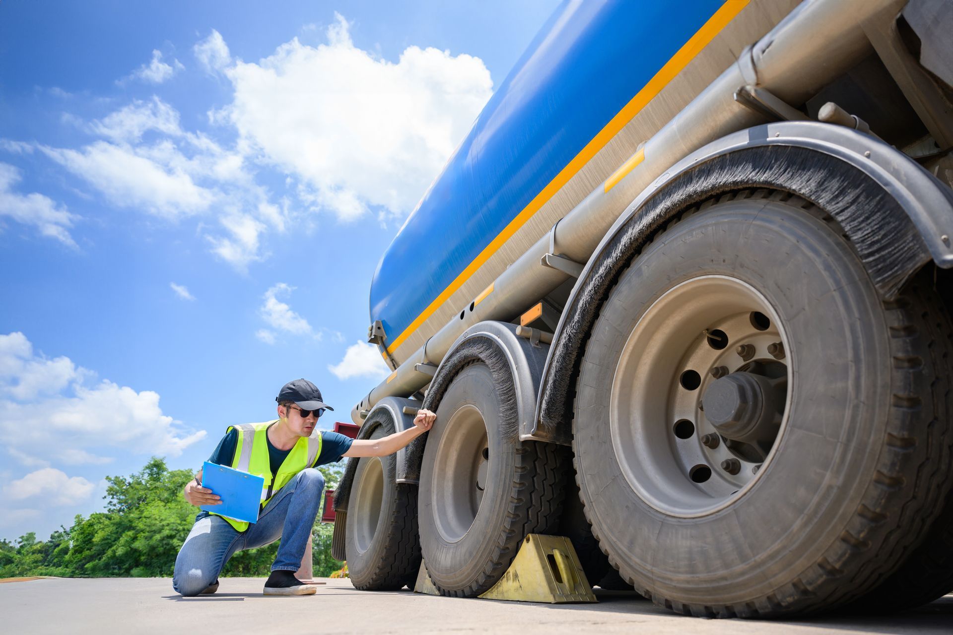 A man is kneeling down next to a large truck.