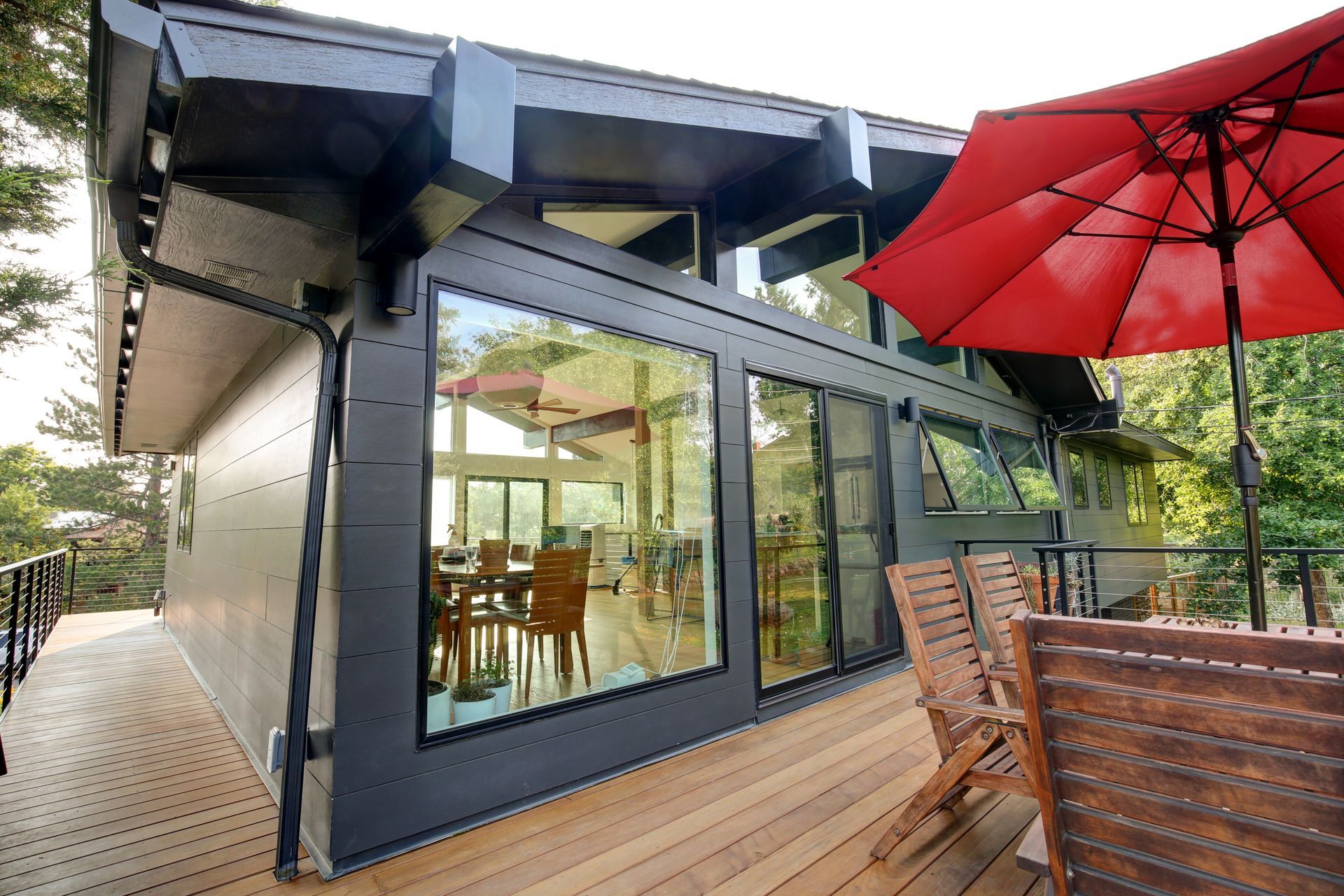 A large house with a large deck and a red umbrella