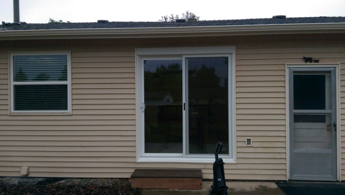 A house with a sliding glass door and two windows.