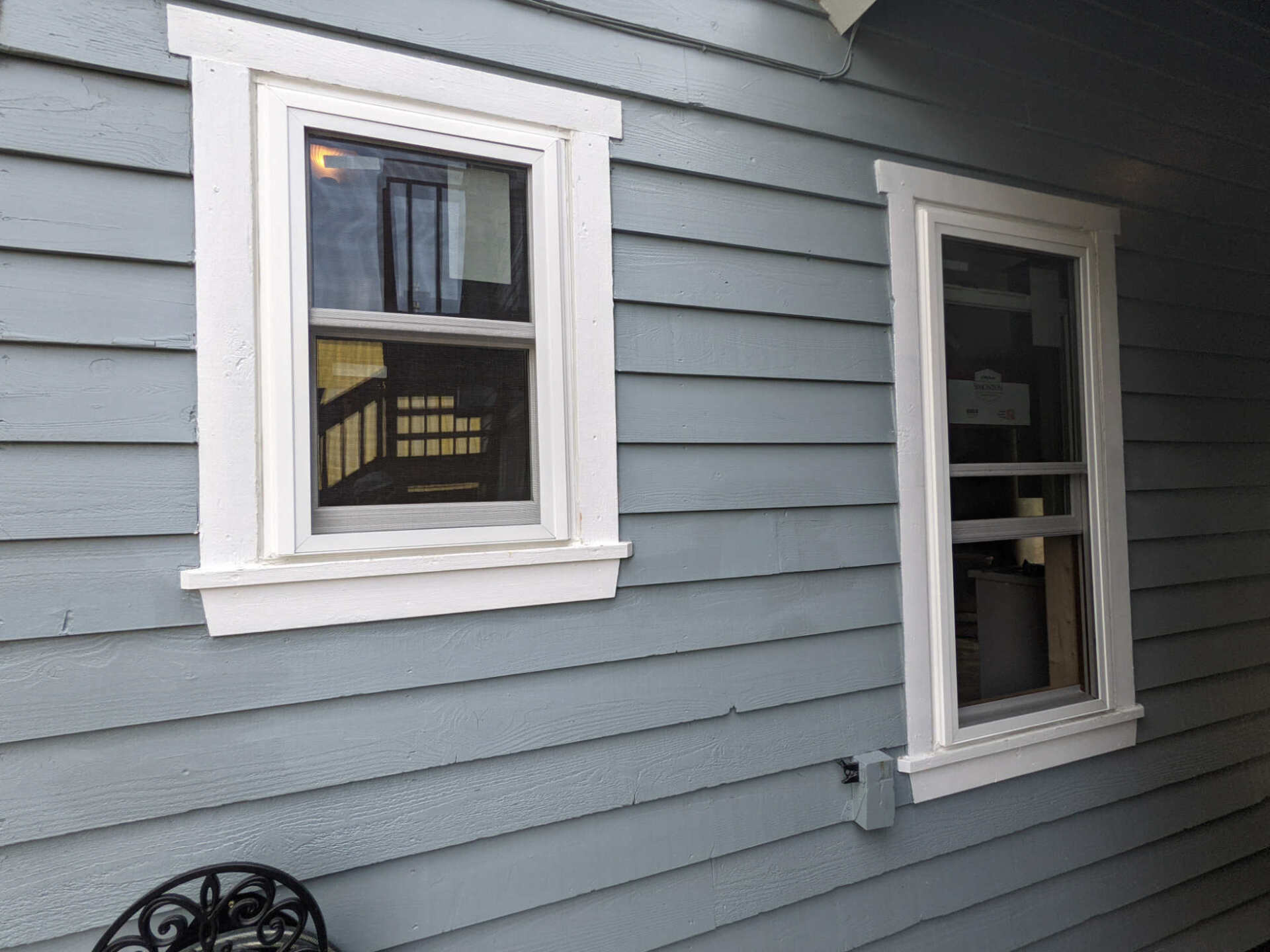 There are two windows on the side of a house.