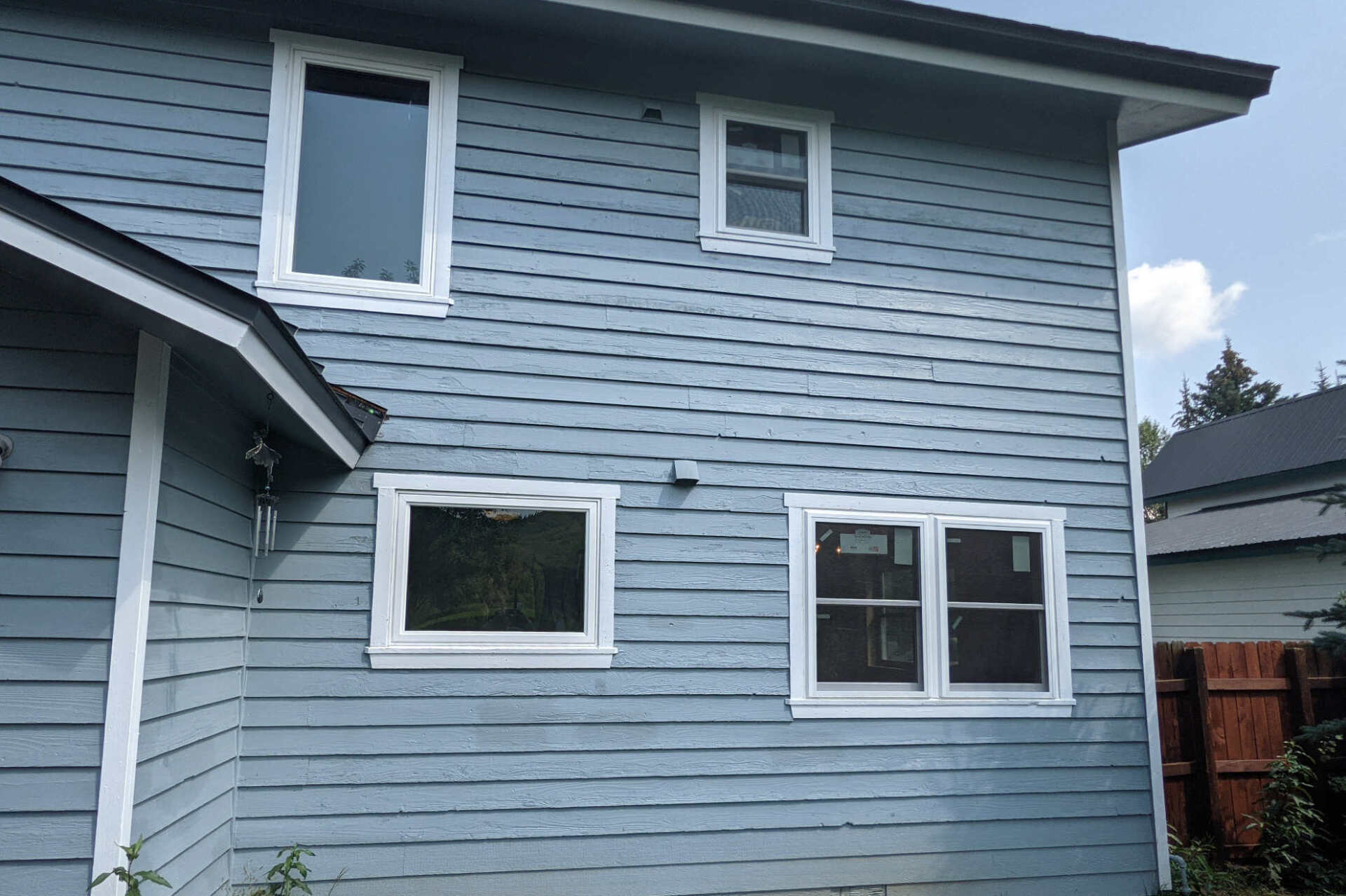 A blue house with white windows and a red fence