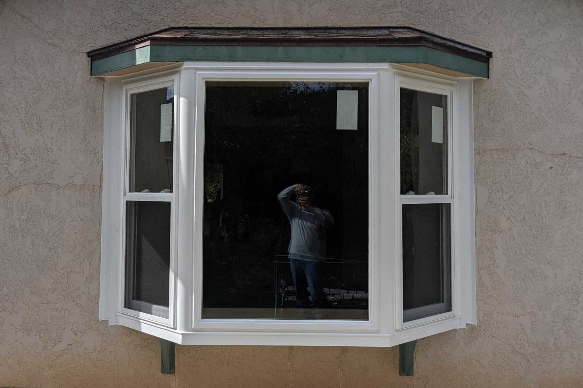 A man is taking a picture of himself in a bay window.