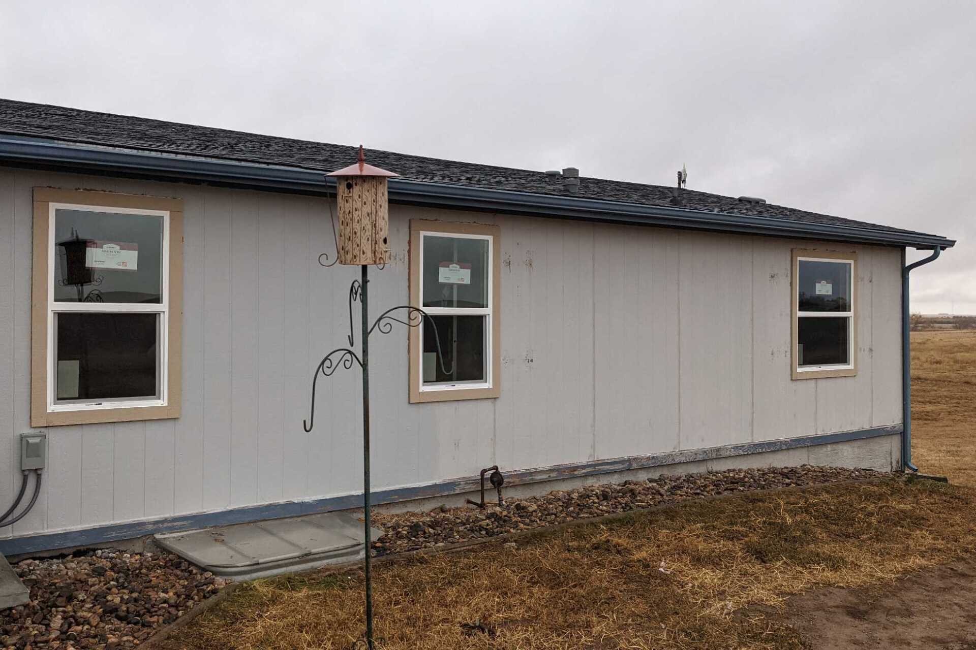 A mobile home with two windows and a bird feeder on the side of it.