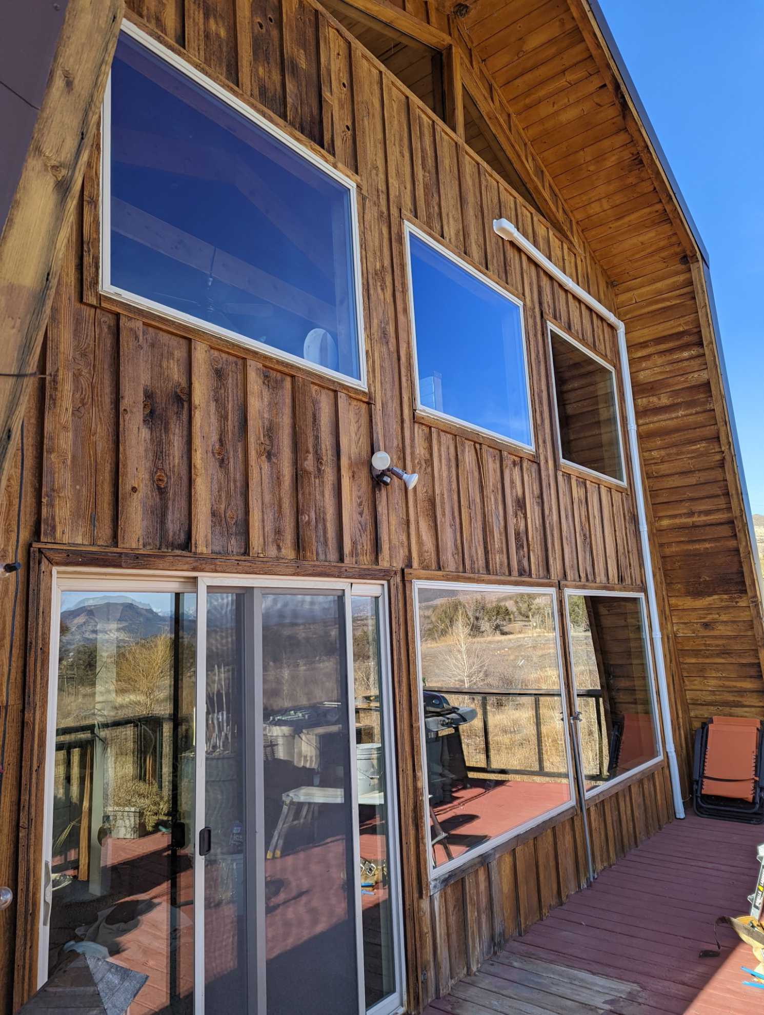 A large wooden house with a lot of windows and a sliding glass door.